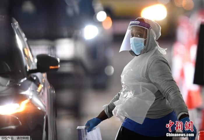 當(dāng)?shù)貢r間12月18日，英國政府公布的數(shù)據(jù)顯示，當(dāng)天英國新增奧密克戎毒株感染病例10059例。鑒于奧密克戎毒株感染病例激增，住院人數(shù)不斷上升，倫敦市長宣布倫敦進入“重大事故”狀態(tài)。圖為倫敦的一個免下車檢測中心，一名醫(yī)務(wù)工作者正準(zhǔn)備對司機進行核酸檢測。