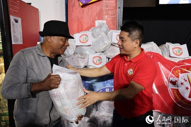 巴西中國(guó)浙江商會(huì)會(huì)長(zhǎng)鄭俠茂向社區(qū)居民轉(zhuǎn)交捐贈(zèng)物資。人民網(wǎng)記者 時(shí)元皓攝