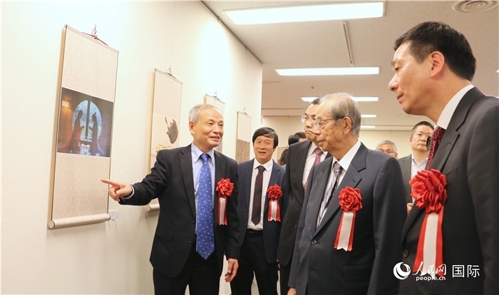 “湖州印象”攝影展主創(chuàng)、世界華人攝影協(xié)會(huì)副會(huì)長馮學(xué)敏向吳江浩大使、福田康夫前首相等嘉賓介紹展出作品。（人民網(wǎng) 許可攝）