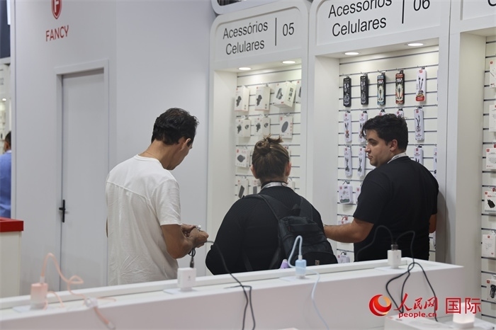 幾名參觀者在一個(gè)展臺(tái)前了解手機(jī)配件。（人民網(wǎng)記者 時(shí)元皓攝）