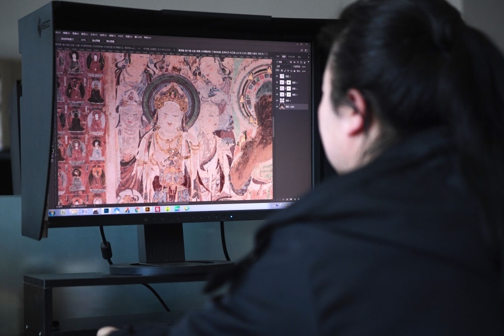 敦煌研究院文物數(shù)字化保護團隊圖像處理人員年海麗在拼接壁畫圖像（2023年4月25日攝）。數(shù)字化探索為莫高窟的保護與傳承開辟了全新路徑，數(shù)字技術讓敦煌文物走出洞窟，跨出國門，走向“永久保存、永續(xù)利用”。新華社記者 陳斌 攝