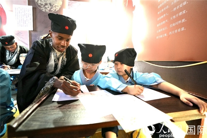 圖為選手與同學們一起寫書法。人民網(wǎng) 盧鵬宇攝