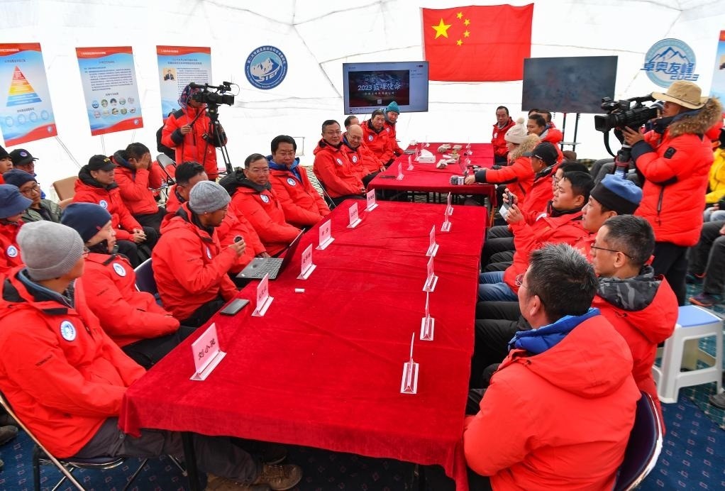 海拔4950米的卓奧友峰科考大本營，科考隊員趙華標(biāo)（手拿麥克風(fēng)看電腦者）在宣讀剛剛接收到的頂峰氣象觀測數(shù)據(jù)，這標(biāo)志著峰頂自動氣象站架設(shè)成功，成功傳回觀測數(shù)據(jù)（10月1日攝）。新華社記者晉美多吉 攝