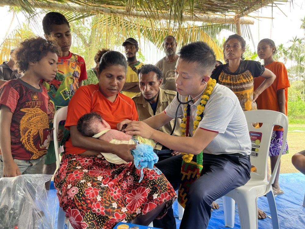 2023年8月5日，在巴布亞新幾內(nèi)亞中央省的一個村莊里，第12批援巴新中國醫(yī)療隊副隊長、新生兒科副主任醫(yī)師劉振球為嬰兒泰樂聽診檢查。泰樂出生時患有重癥，一度生命垂危，經(jīng)過劉振球與當?shù)蒯t(yī)護人員的救治最終痊愈。從2002年起，中國連續(xù)向巴新派出12批醫(yī)療隊，為提高巴新醫(yī)療衛(wèi)生水平作出積極貢獻。