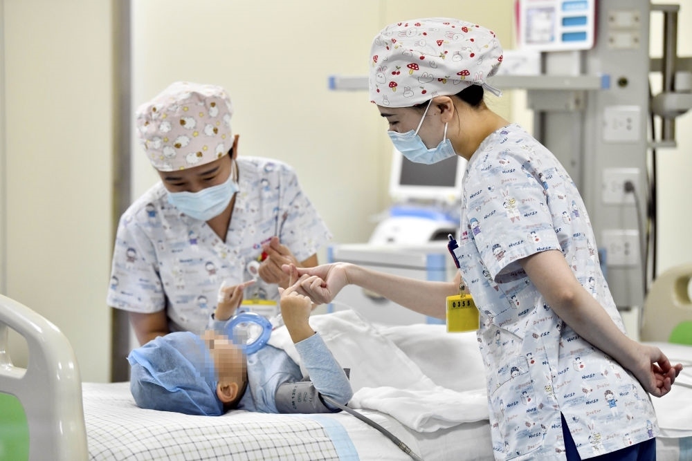 在山東省棗莊市婦幼保健院兒童ICU病房，醫(yī)護人員為完成靶向治療藥物諾西那生鈉的4歲脊髓性肌萎縮癥患兒加油鼓勁（2022年1月1日攝）。諾西那生鈉注射液是我國首個獲批治療脊髓性肌萎縮癥的進口藥物，2019年進入中國市場時，每針價格近70萬元。在2021年國家醫(yī)保目錄藥品談判中，以3.3萬元每針的價格進入新版醫(yī)保藥品目錄。新華社記者 郭緒雷 攝