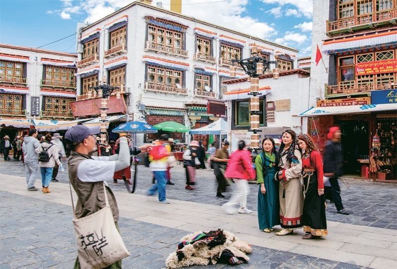 千年八廓街，見證民族團(tuán)結(jié)。2021年7月，習(xí)近平總書記來(lái)到位于西藏拉薩老城區(qū)的八廓街，感慨地說(shuō)：“千年八廓街，是我們各民族建起來(lái)的八廓街。各民族文化在這里交流交往交融，我們中華民族的大家庭在這里其樂融融?！眻D為2023年6月13日，游客身著藏裝在八廓街拍照留念。 新華社記者 姜帆/攝