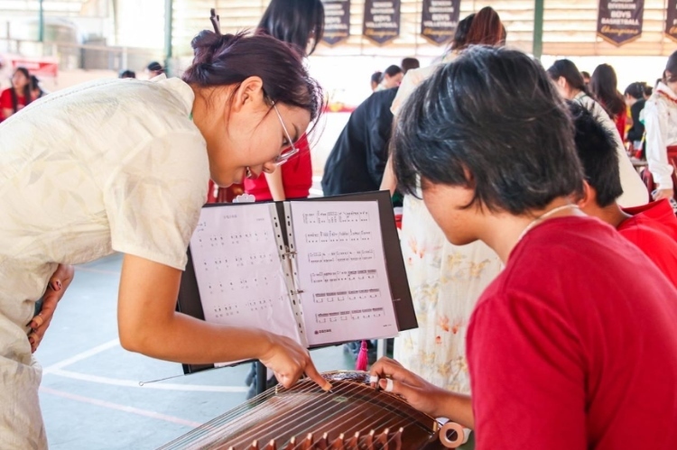 志愿者教師指導(dǎo)學(xué)生彈奏古箏?；顒又鬓k方供圖