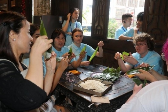 6月9日，美國青年代表在重慶永川松溉古鎮(zhèn)體驗包粽子。新華社記者 周思宇 攝