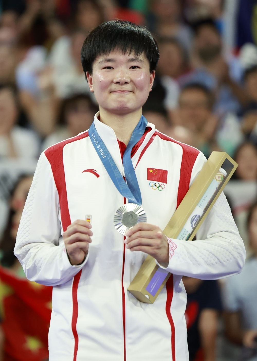 巴黎奧運會羽毛球女子單打亞軍、中國選手何冰嬌在頒獎儀式上一手握著銀牌，一手握著西班牙奧委會徽章（2024年8月5日攝）。新華社記者 任正來 攝