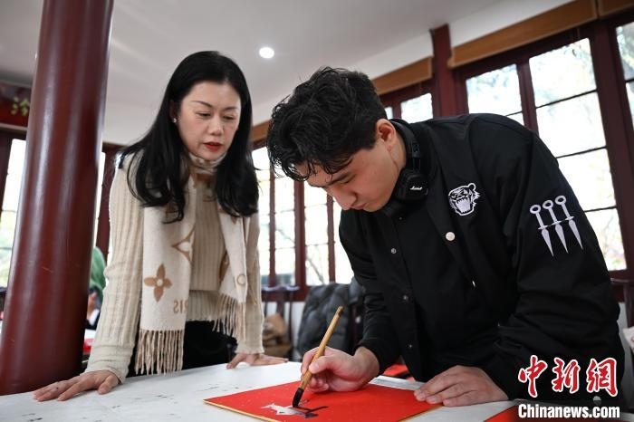 1月20日，外籍留學(xué)生在西泠印社社員李硯指導(dǎo)下寫福。當(dāng)日，來(lái)自巴西、馬來(lái)西亞、加納、哈薩克斯坦的外籍留學(xué)生在浙江杭州西泠印社體驗(yàn)福貼、春聯(lián)和篆刻，感受古老的中國(guó)傳統(tǒng)文化。中新社記者 王剛 攝