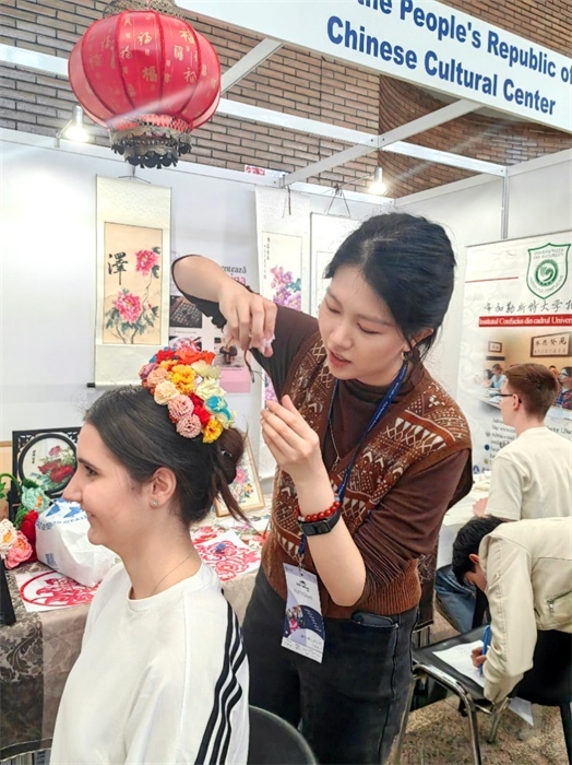 展覽正值羅馬尼亞迎春花節(jié)，國際中文教師志愿者潘婧穎向游客們介紹了國家非物質(zhì)文化遺產(chǎn)——福建泉州的簪花文化。布加勒斯特大學(xué)孔子學(xué)院供圖。