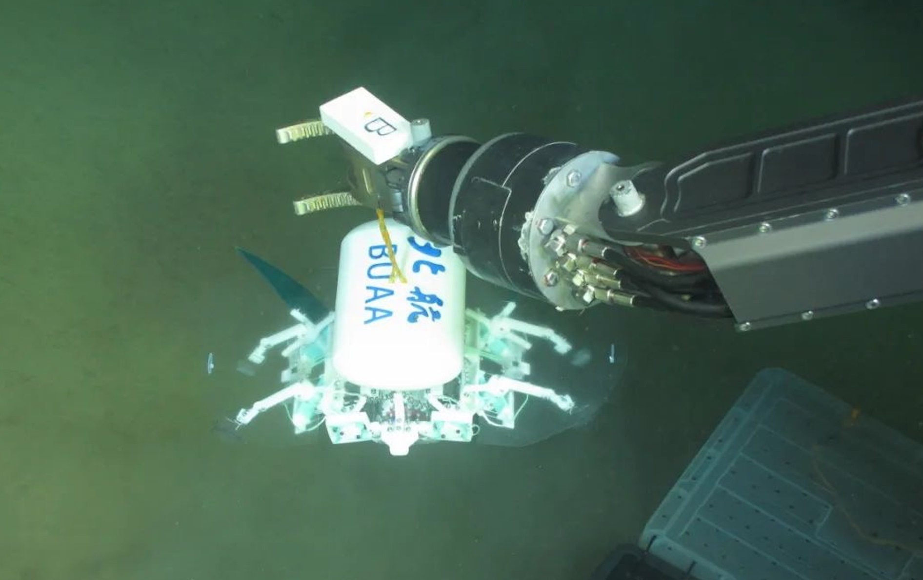 科研人員利用機械臂將北航深海小型機器人投于馬里亞納海溝。校方供圖