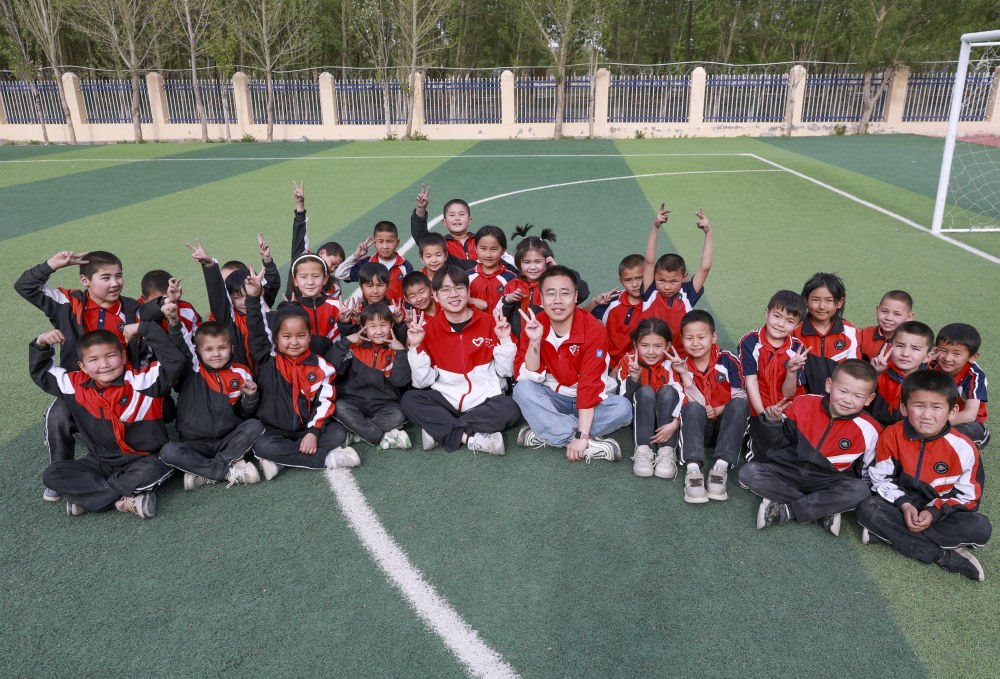 4月23日，在新疆克州阿圖什市哈拉峻鄉(xiāng)謝依特小學(xué)，支教教師王俊文（中左）、李軻凡（中右）和學(xué)生在一起。