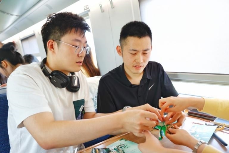 G232次旅客親手制作端午荷包和五彩繩。王磊攝